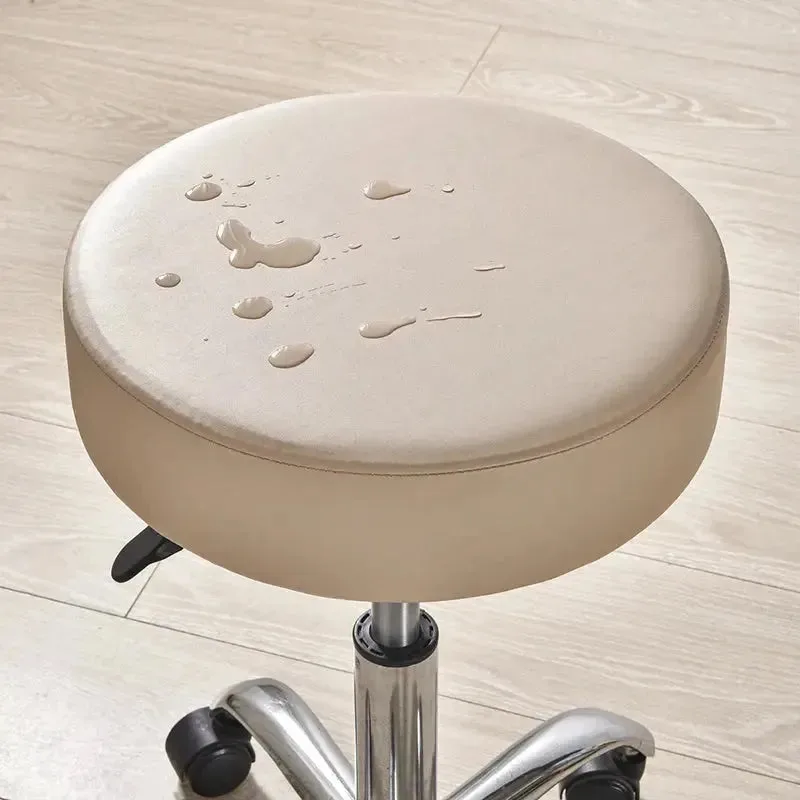 Waterdichte hoes op ronde kruk, beige, met waterdruppels.