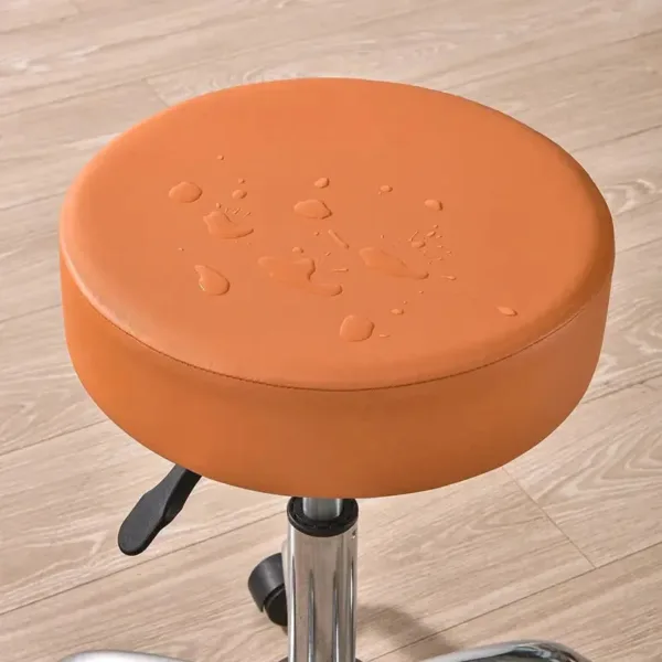Oranje waterdichte hoes op ronde kruk, waterdruppels op zitting.